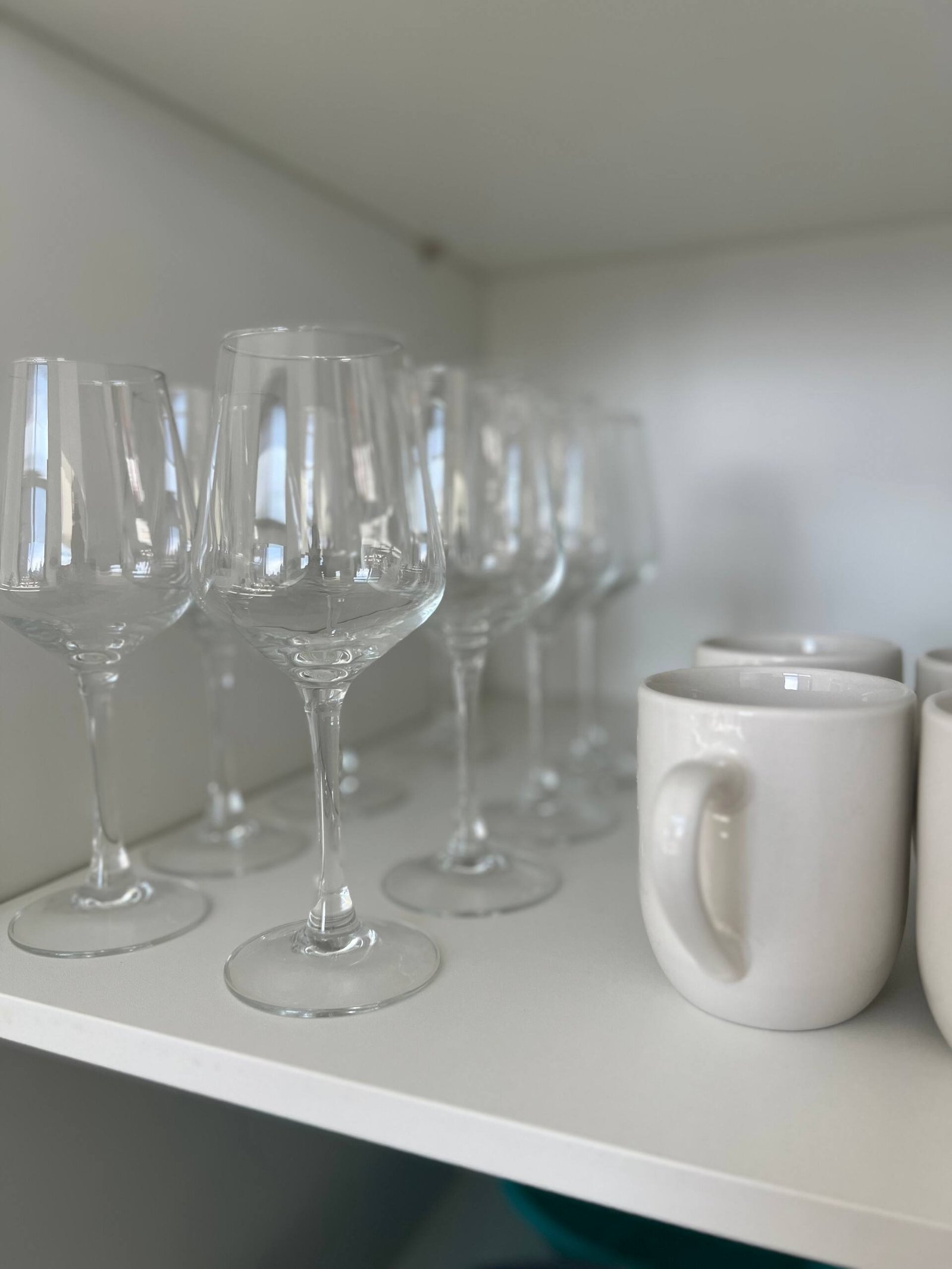 Glassware and mugs stocked in the kitchen cabinet