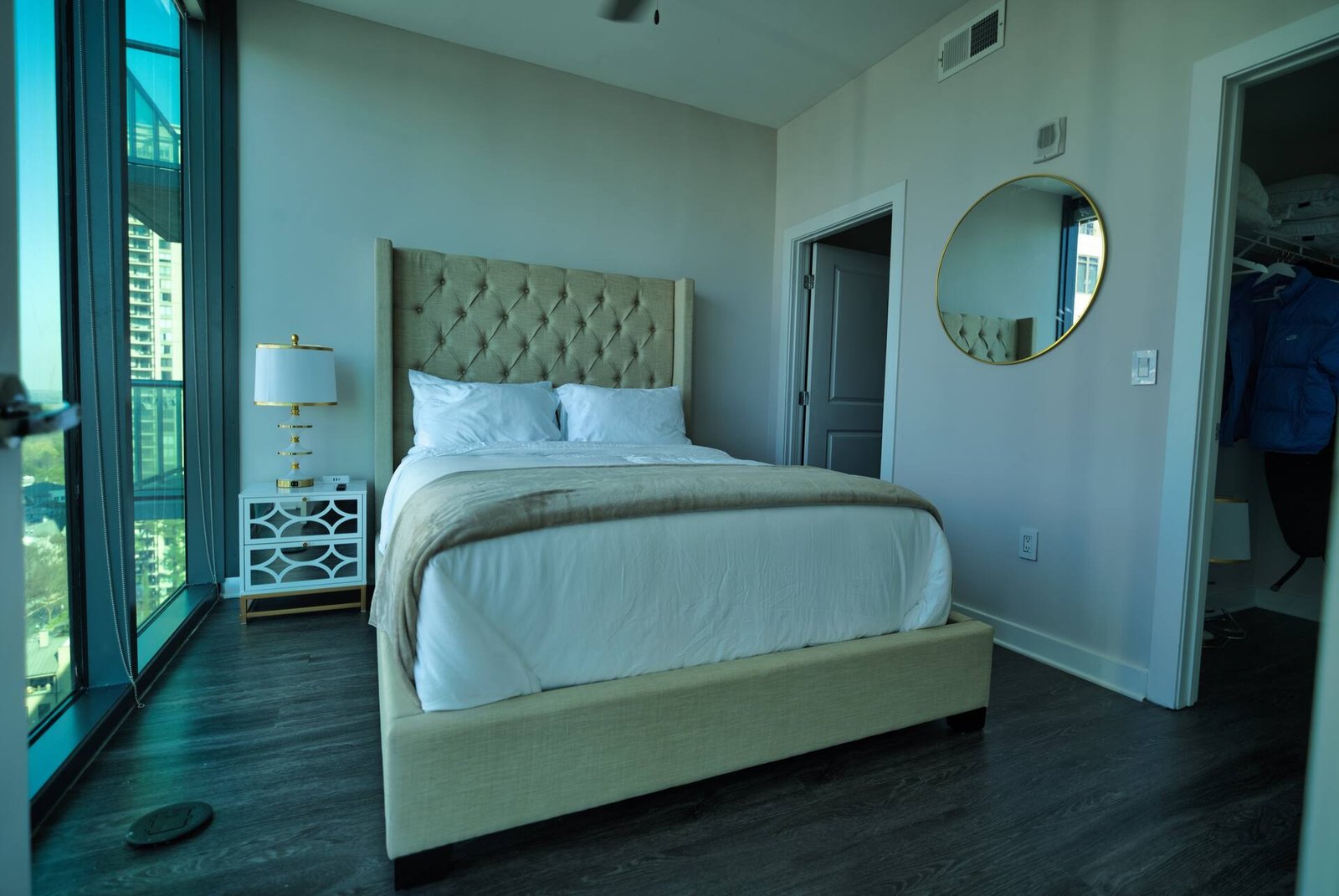 Bedroom with round mirror and floor-to-ceiling glass